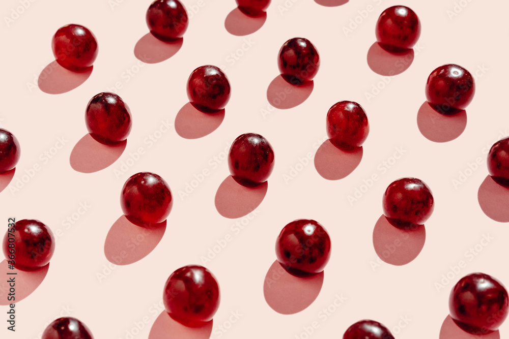 From above pattern of fresh red grapes arranged in lines on pink surface in studio From above pattern of fresh red grapes arranged in lines on pink surface in studio