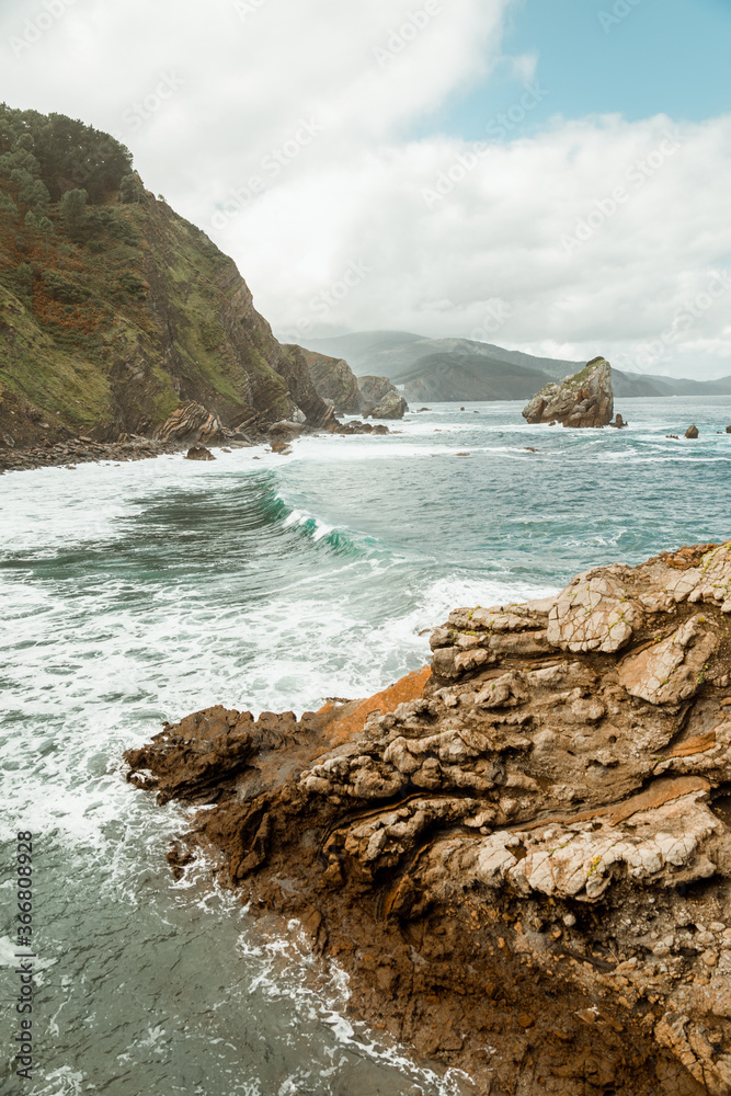 Top view of troubled turquoise sea with waves passing between natural rocky formations with shabby uneven surface Top view of troubled turquoise sea with waves passing between natural rocky formations with shabby uneven surface