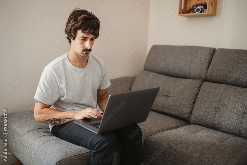 Side view of concentrated male entrepreneur using laptop while working on remote project at home Side view of concentrated male entrepreneur using laptop while working on remote project at home