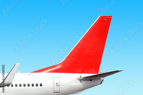 modern airplane tail side with white aircraft body red fin and white winglet isolated on blue sky background. Parts of passenger jet plane. Aviation wallpaper Blank copy space design template