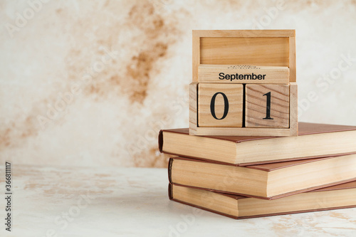 Wooden calendar September 1 on a stack of books. Concept for Knowledge Day, beginning of school year. Copy space.