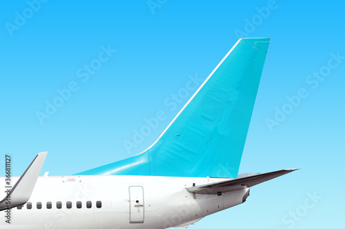 Фотография modern airplane tail side with white aircraft body light blue fin and white winglet isolated on blue sky background
