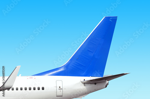 modern airplane tail side with white aircraft body blue fin and white winglet isolated on blue sky background. Parts of passenger jet plane. Aviation wallpaper Blank copy space design template