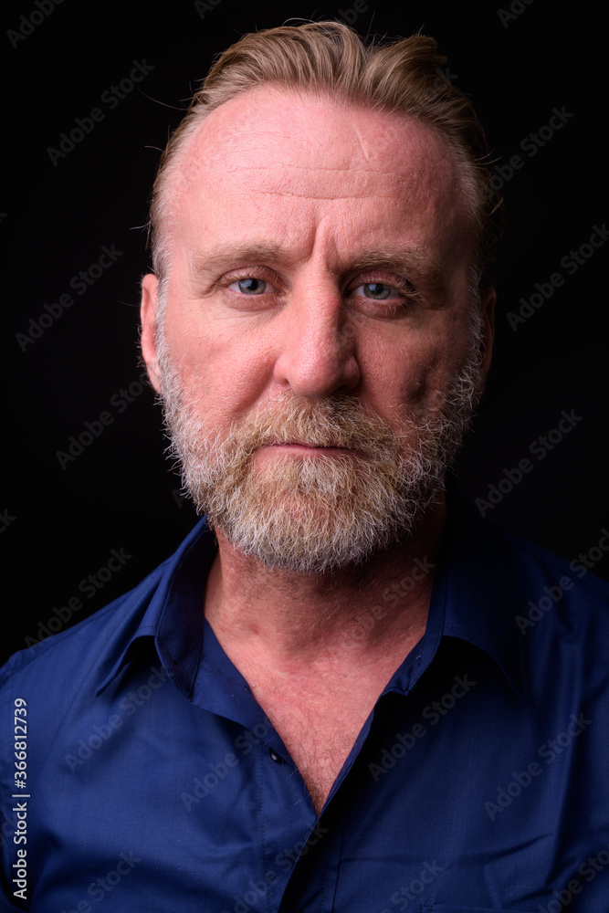 Mature handsome bearded man with blond hair against black background Mature handsome bearded man with blond hair against black background