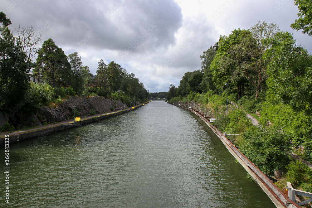 View of the Gota river that flows through western Sweden. There is an embankment on the left side and otherwise surrounded by trees and foliage View of the Gota river that flows through western Sweden. There is an embankment on the left side and otherwise surrounded by trees and foliage