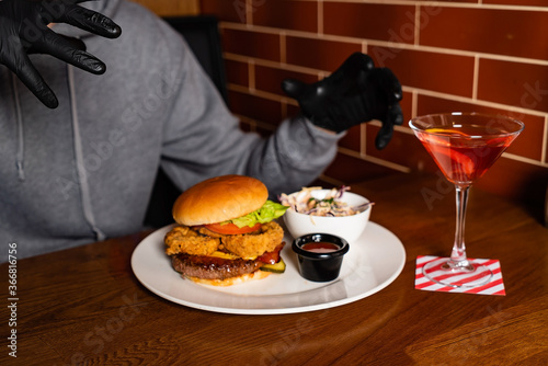 man in black gloves eating burger in the restaurant