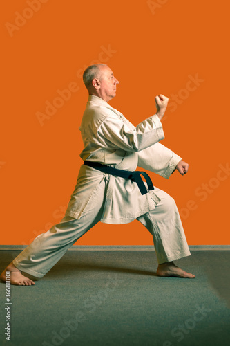 A karate man in a white kimono with a black belt is preparing for the competition.
