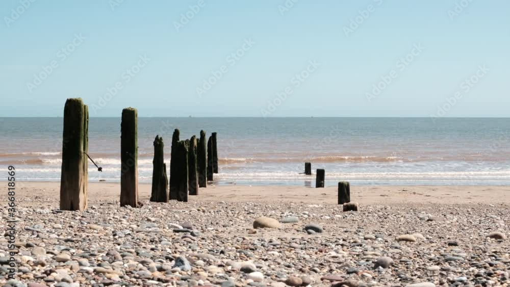 Slow motion wide clip of weathered and green covered wooden pillars forming Beach Erosion Protection along the coast at Spurn Head on the Humber Estuary in England. North Sea waves crashing Slow motion wide clip of weathered and green covered wooden pillars forming Beach Erosion Protection along the coast at Spurn Head on the Humber Estuary in England. North Sea waves crashing