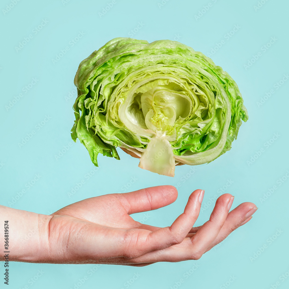 Obraz premium Balanced nutrition, diet or weight loss concept. Female hand and lettuce on a blue background. Vegan food.