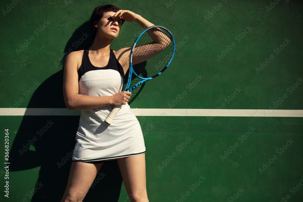 woman wearing white tennis dress posing on green tennis wall
