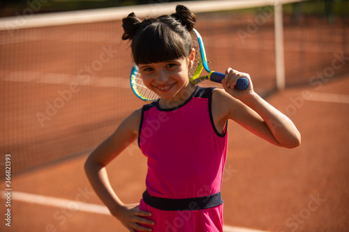 portrait of a cute girl and wearing her tennis racket behind her head © kevin