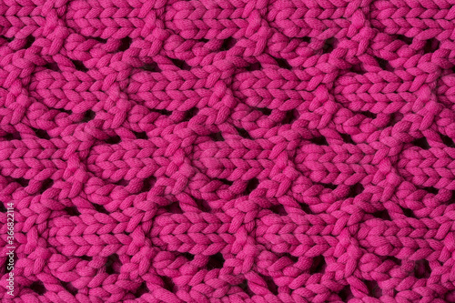 The texture of the knitted with the ornament of purple woolen fabric. Background, pattern, design. © Arina B
