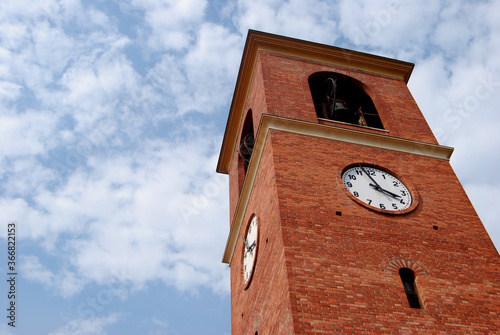  red brick bell tower with clock on blue sky background