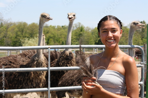 Happy teenager girl is holding ostrich feathers visiting an ostrich farm photo