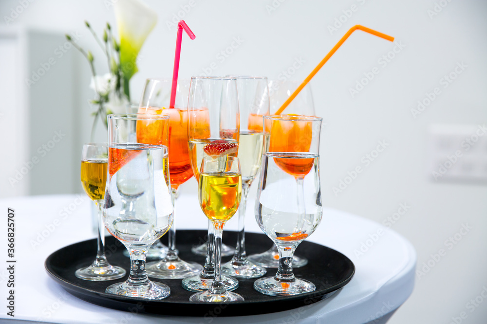 Rows of glasses with orange drink and ice cubes