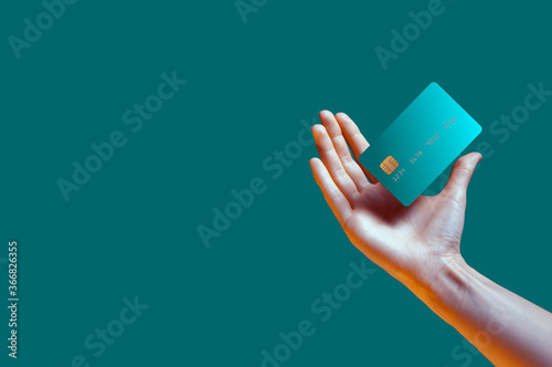 Close up female hand holds levitating template mockup Bank credit card with online service isolated on green background photo