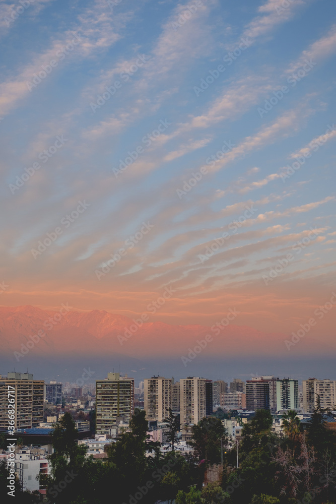 Beautiful pattern of clouds and sunset sky over Santiago downtown and The Andes Mountains with golden sunlight, Chile	