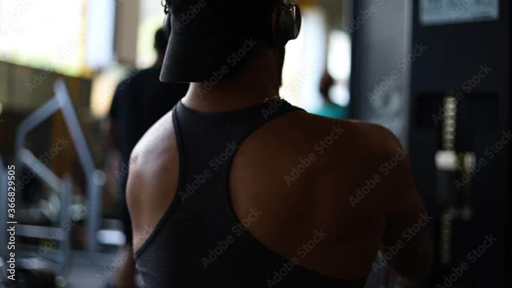 Young strong Caucasian man sitting on workout bench in gym pulling weights towards chest working upper body and shoulder muscles, close up pan Young strong Caucasian man sitting on workout bench in gym pulling weights towards chest working upper body and shoulder muscles, close up pan