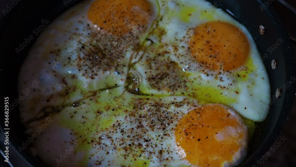 Cooking fried eggs on a pan with spices.