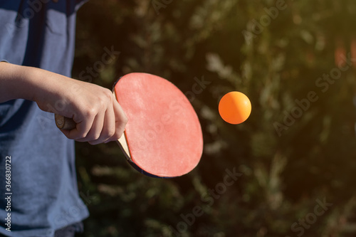 A boy playing table tennis, ping pong outside in the garden.