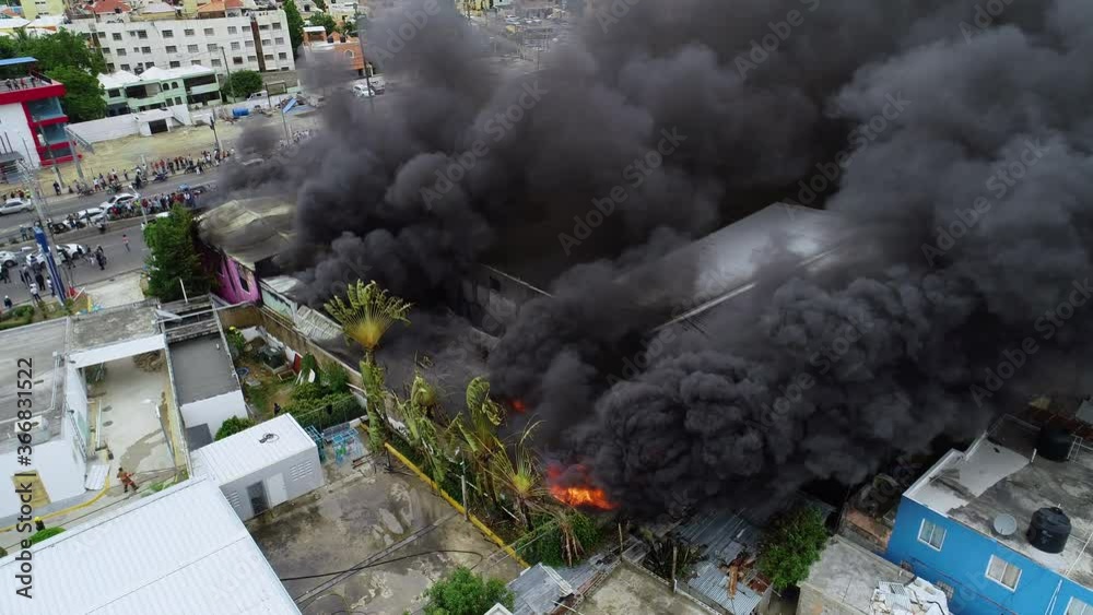 Aerial orbit, drone shot around a building fire, a big black smoke cloud rising from a burning structure, in Abuja, Nigeria, Africa