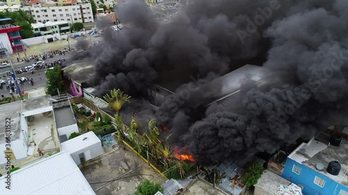 Aerial orbit, drone shot around a building fire, a big black smoke cloud rising from a burning structure, in Abuja, Nigeria, Africa photo