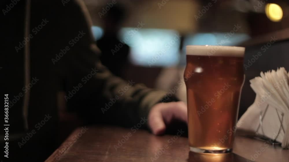 Waitress serves a glass of craft beer to client at a bar/pub.