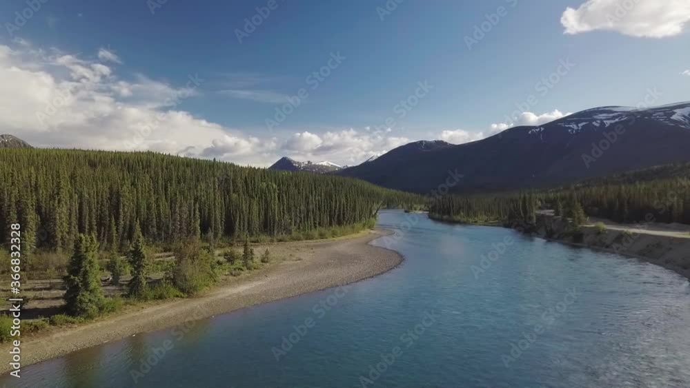 Spectacular panoramic flight above Yukon Takhini river, green forest landscape, camping site and mountain range on sunny blue sky day, Canada, overhead aerial pull back Spectacular panoramic flight above Yukon Takhini river, green forest landscape, camping site and mountain range on sunny blue sky day, Canada, overhead aerial pull back