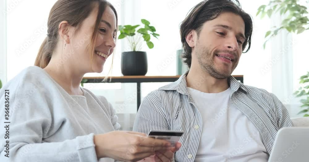 Excited couple celebrating success while online shopping with credit card and laptop Excited couple celebrating success while online shopping with credit card and laptop