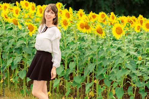 young woman in a field of sunflowers. rural girl in the field. sunflowers in the field. sunflower summer landscape. sky, field, flowers. fruitful summer. harvesting. agricultural work