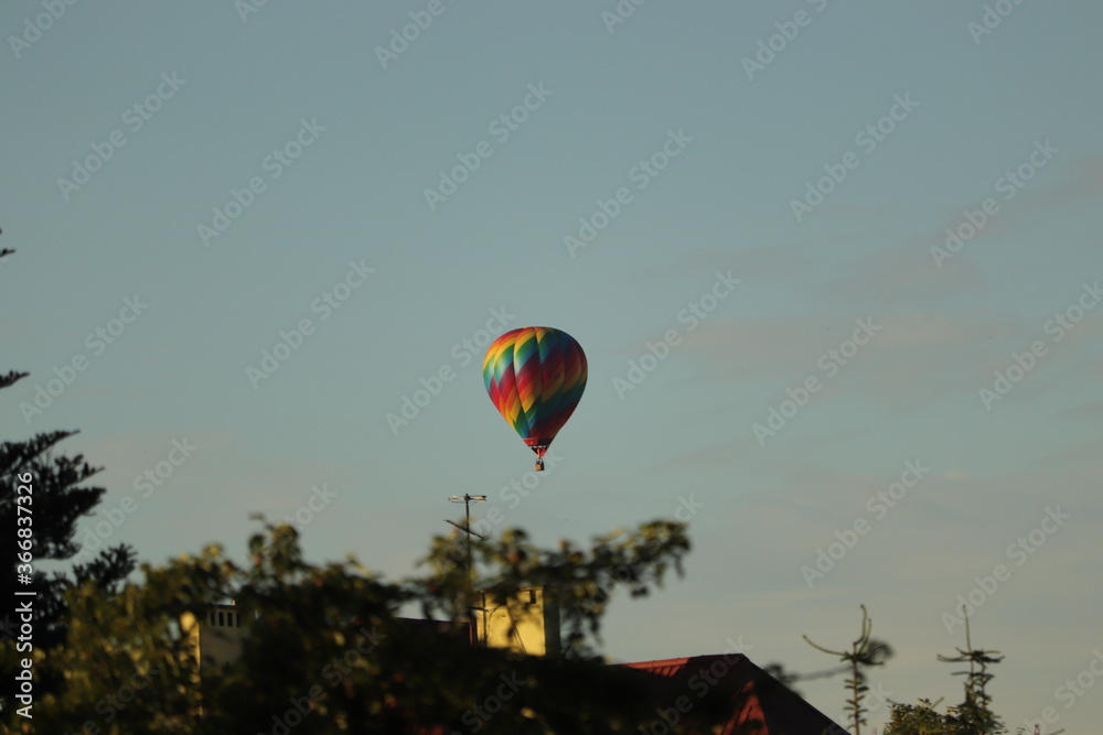 lot  kolorowym  balonem  wysoko  nad  miastem - obrazy, fototapety, plakaty 