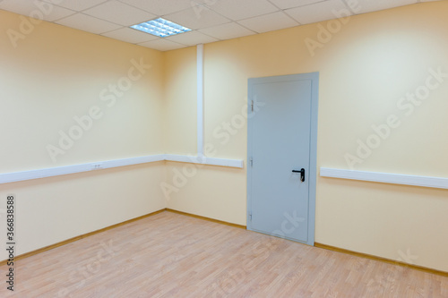 An empty room with a metal door and no windows.