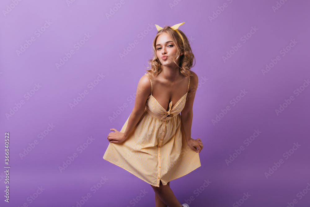 Beautiful good-humoured girl funny posing on purple background. European fair-haired woman looking to camera with kissing face expression. Beautiful good-humoured girl funny posing on purple background. European fair-haired woman looking to camera with kissing face expression.