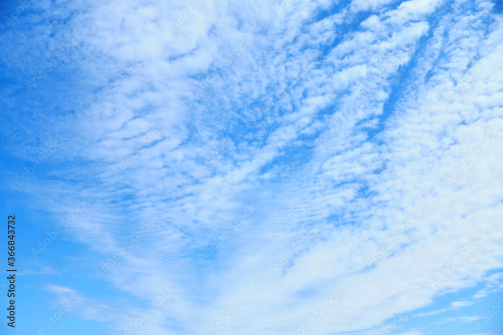 Blue summer sky with stretched and blurred white clouds