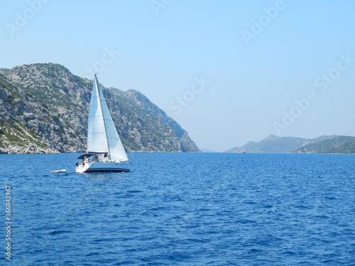 Small white yacht floats near the rocky shores, sea, rocks