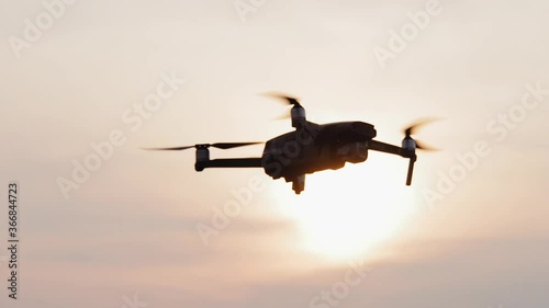 Low-altitude flight of the DJI Mavic 2 quadrocopter against the backdrop of the sunset, silhouette. photo