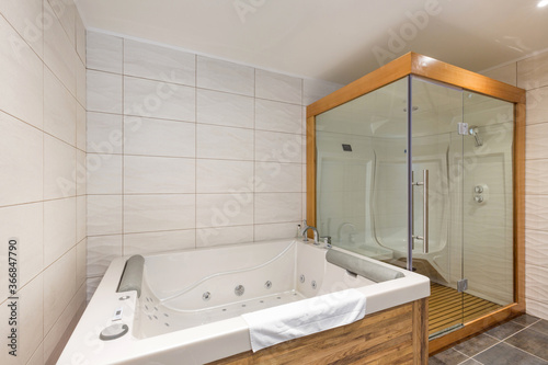 interior of luxury hotel bathroom with hydromassage bathtub and shower cabin