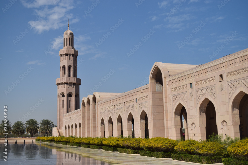 The stunning Sultan Qaboos Grand Mosque with its beautiful minaret and arches in contrast with blue sky.