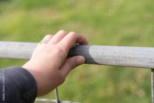 Hand on metal farm fence. Concept. opening fence. 