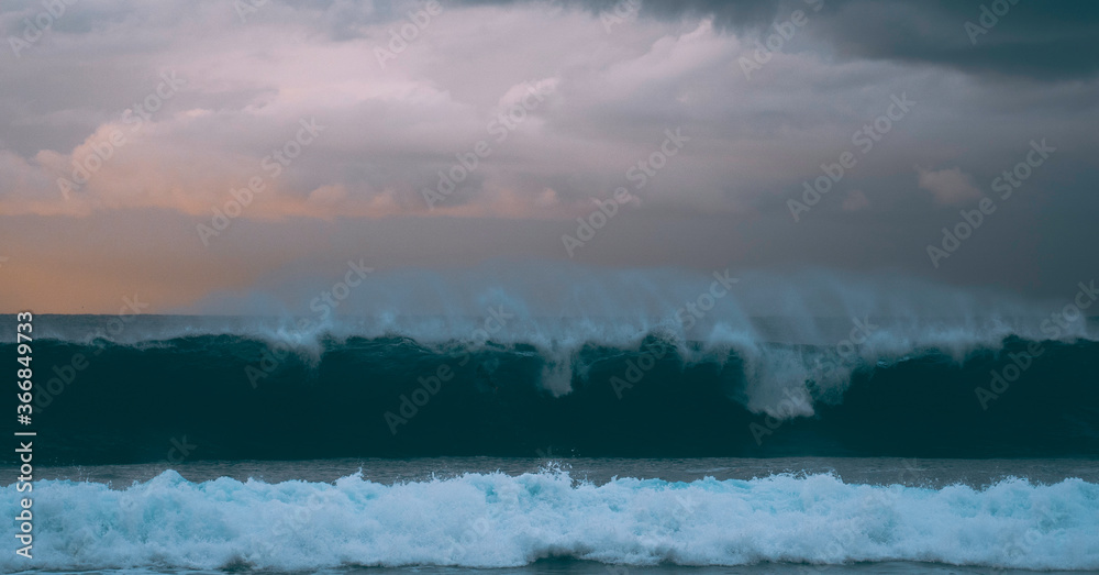 mist over the ocean as a big wave comes rolling into shore at sunrise