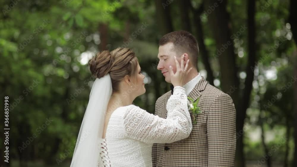 Newlyweds. Caucasian groom with bride making a kiss in park. Wedding couple. Man and woman in love