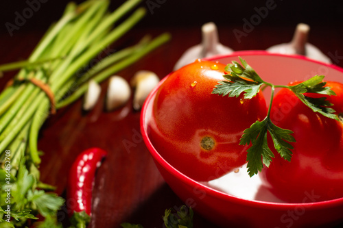 Composição com tomates vermelhos, legumes e legumes em um fundo de madeira. Tomate com gotas de água