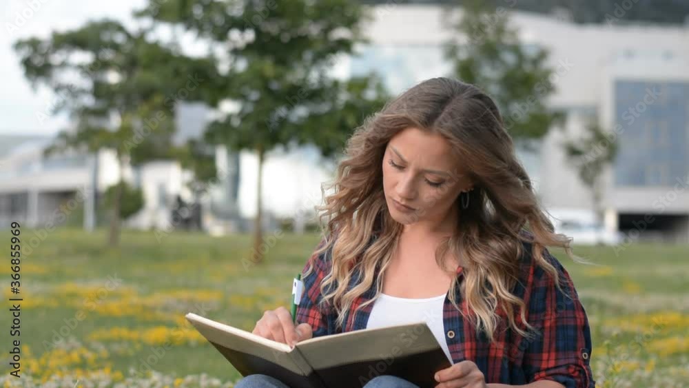 Beautiful Caucasian Young Girl Sitting On Grass At Park And Writing In Diary important notes Beautiful Caucasian Young Girl Sitting On Grass At Park And Writing In Diary important notes