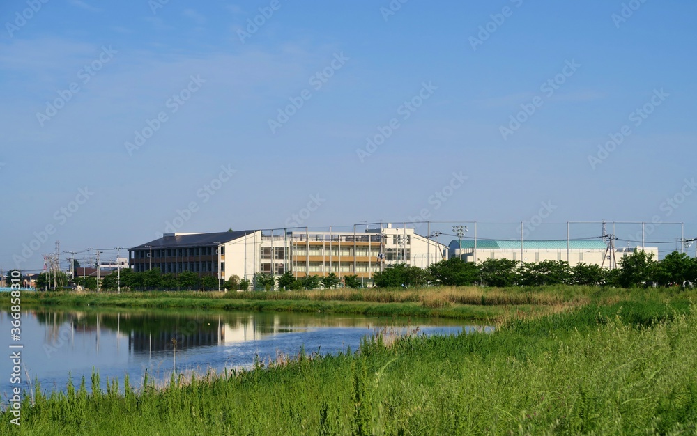 古利根川越しに見える休校中の埼玉県春日部市の中学校の遠景。