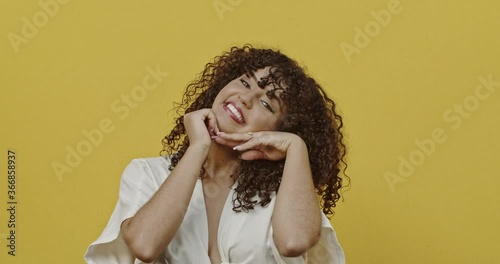 Portrait of cute woman smiling with white perfect teeth saying yes and nodding positively meaning agreement over yellow background. Concept of emotions. 4K.