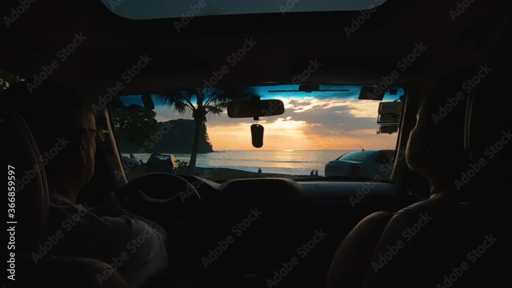 Sunset from inside a vehicle, while family gets to park on the beach