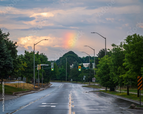 Rainbow in a sunset sky over a road in North American suburbia