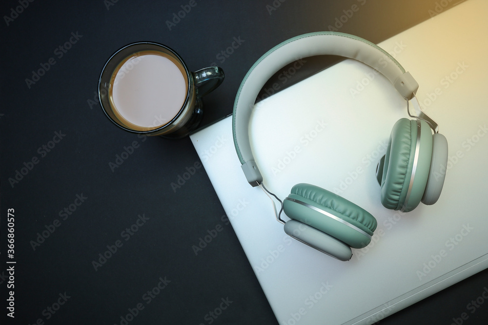 Headphone on the laptop and a mug of coffee on black background Headphone on the laptop and a mug of coffee on black background