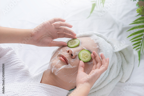 Beautiful asian woman healthcare in the spa salon, Treatment eye dark circles and hyperpigmentation on face by cucumber slice and serum mask, Facial rejuvenation procedure.