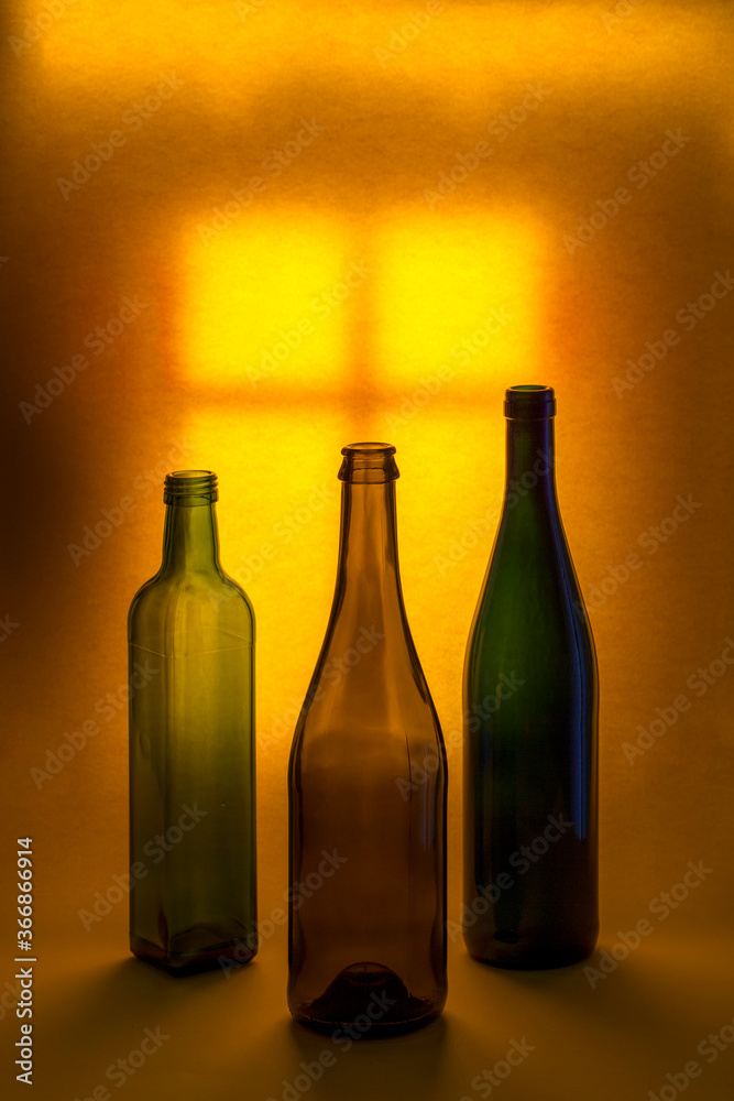 Still life with colored bottles against the background of a lighted window Still life with colored bottles against the background of a lighted window